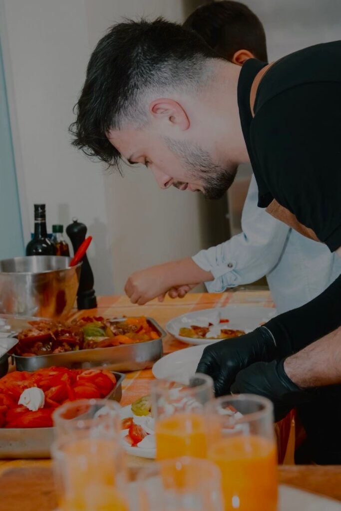 Homme en tablier préparant des plats dans une cuisine avec verres de jus à l'avant