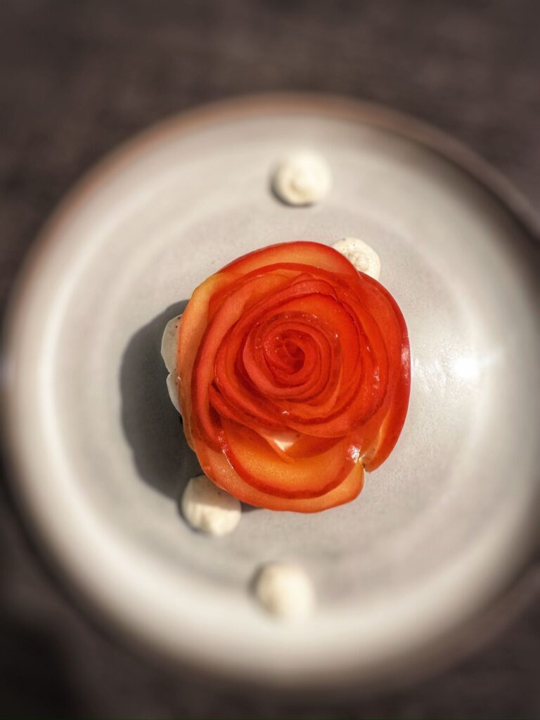 Plat gastronomique decoré en forme de rose rouge sur assiette blanche avec sauce