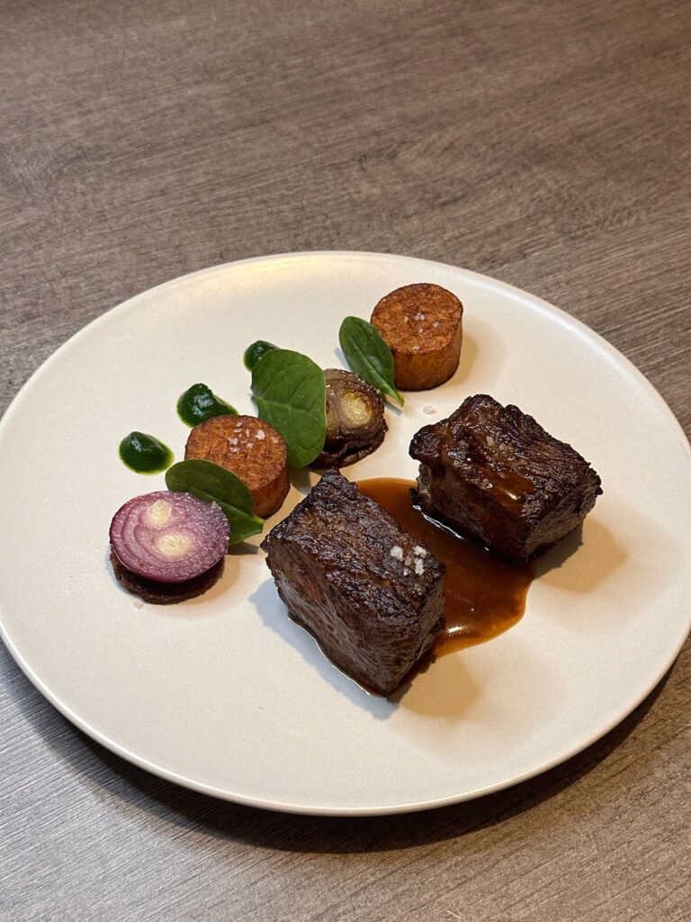 Plat gastronomique avec viande braisée et légumes présentés avec sauce