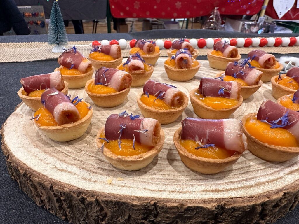 Tartelettes apéritives garnies de purée orange et roulés de viande sur planche en bois