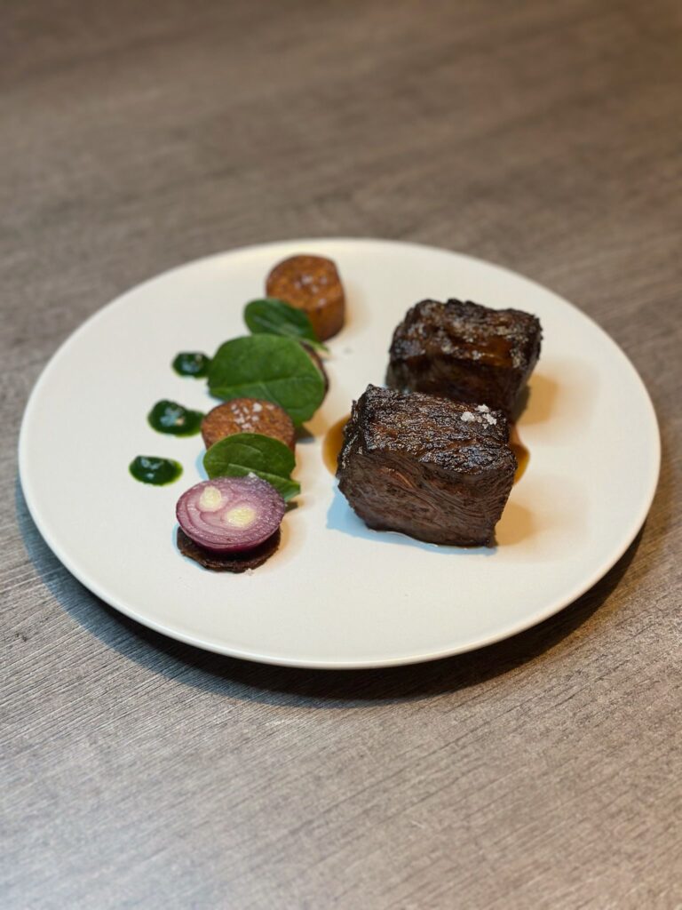 Plat gastronomique avec viande grillée et garniture de légumes verts et patate douce