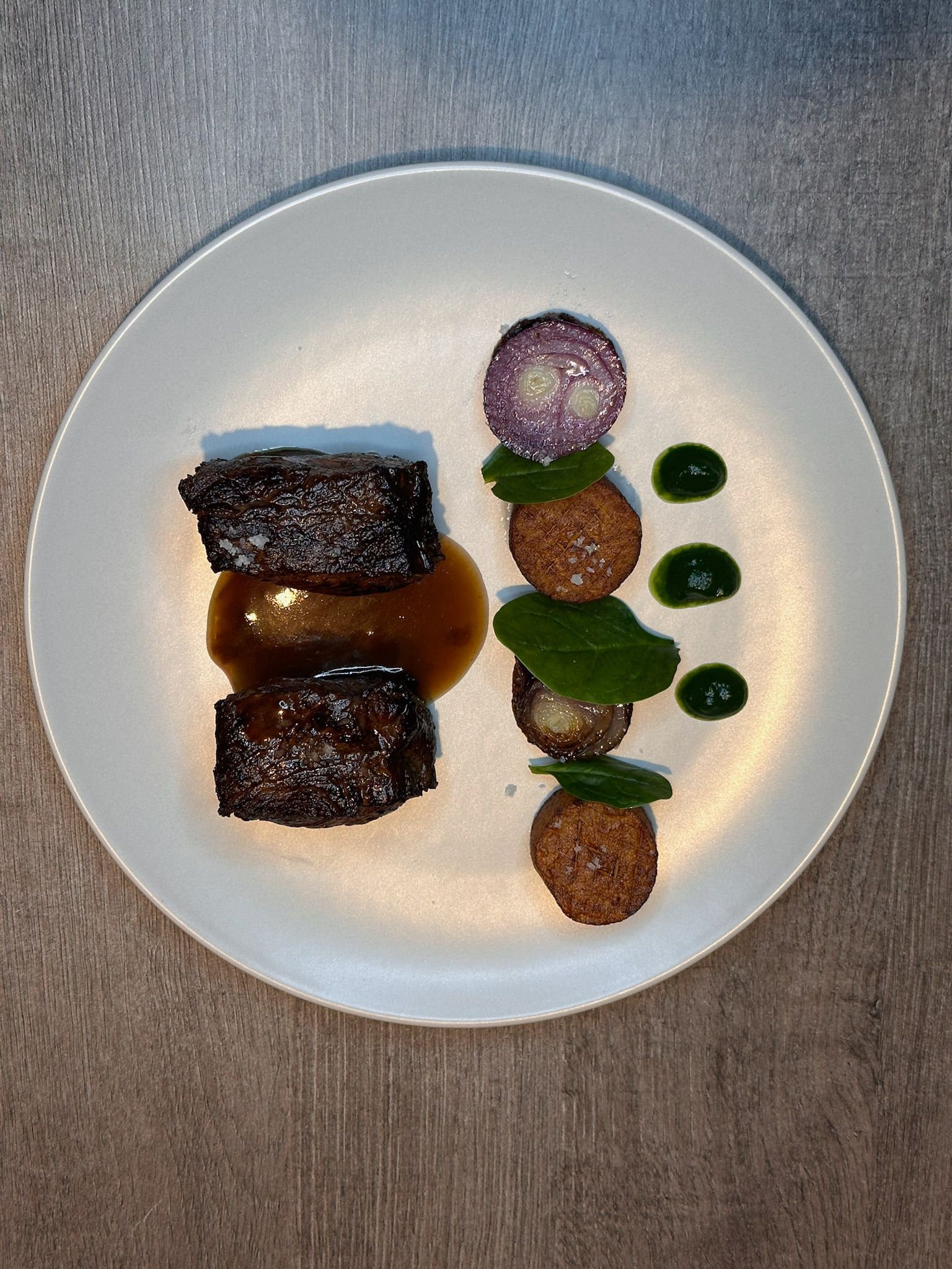 Plat gastronomique avec viande en sauce, légumes rôtis et feuilles vertes en présentation soignée