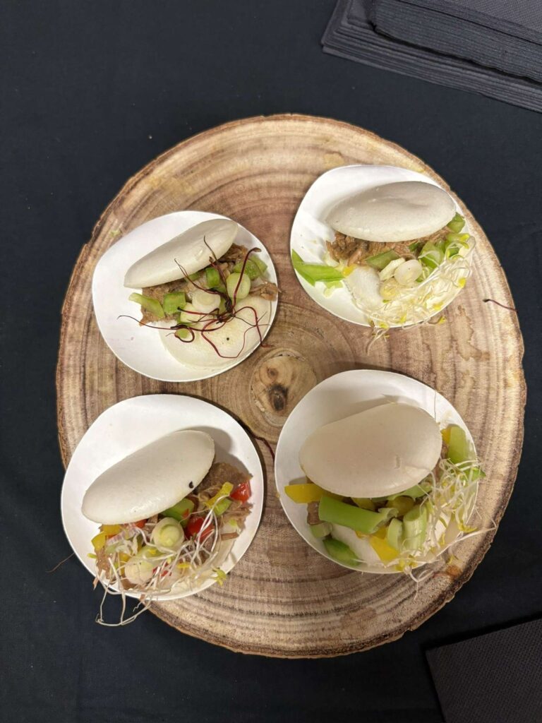 Quatre petits sandwichs vapeurs garnis de viande et légumes sur une planche en bois