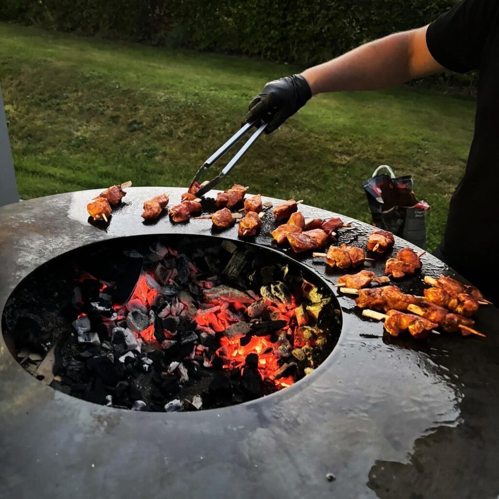 Brochettes de viande grillant au barbecue à charbon dans un jardin