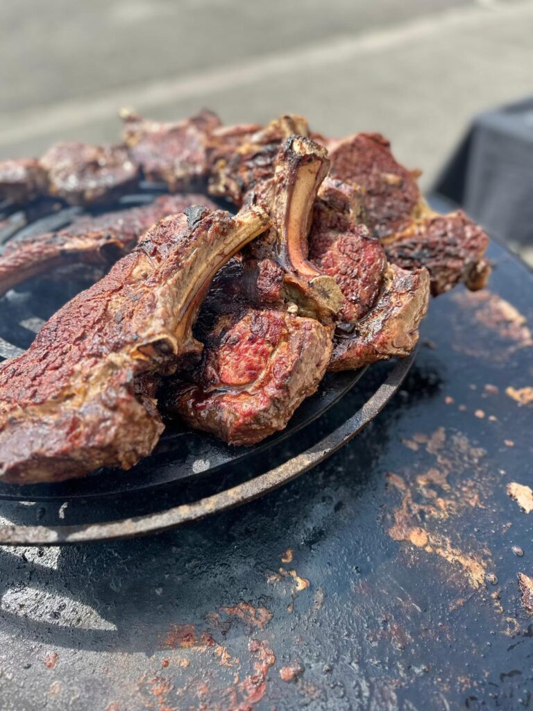 Viande rouge avec os en cuisson sur un gril extérieur pour barbecue