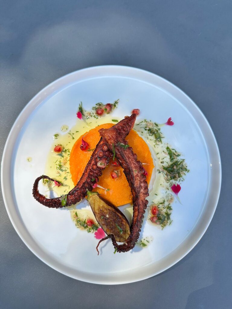 Plat gastronomique de poulpe grillé avec purée orange, aubergine et décorations fines
