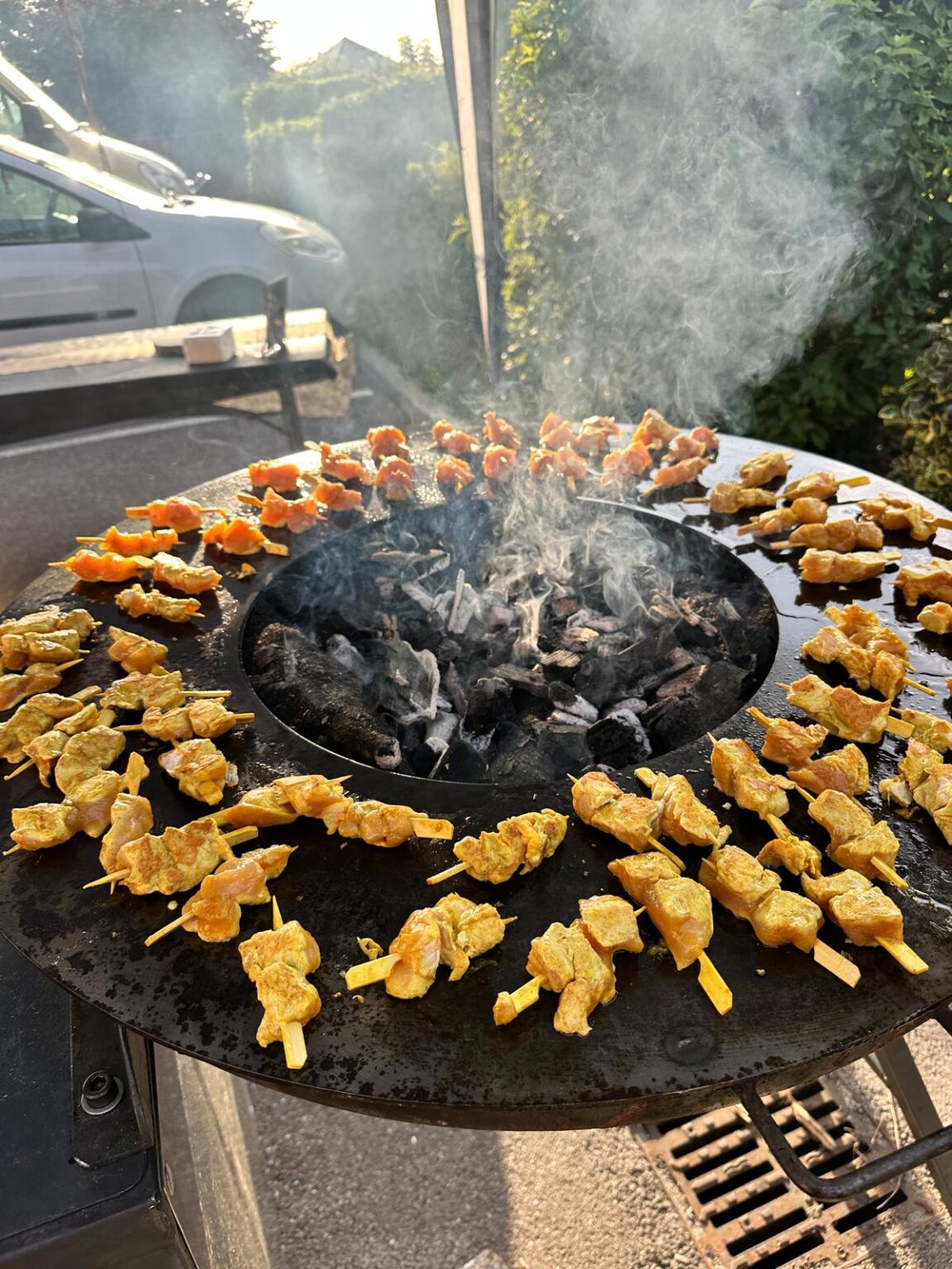 Brochettes de viande grillant sur plaque circulaire à charbon avec de la fumée