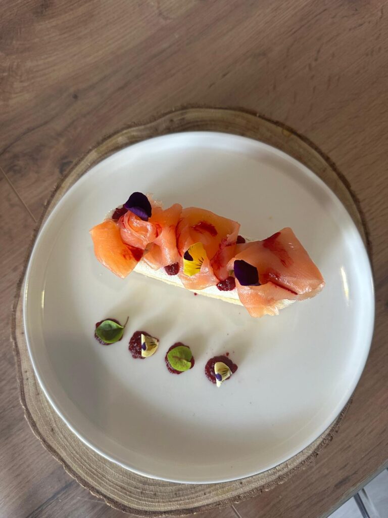 Entrée raffinée de saumon fumé avec fleurs comestibles et purée rouge sur assiette blanche
