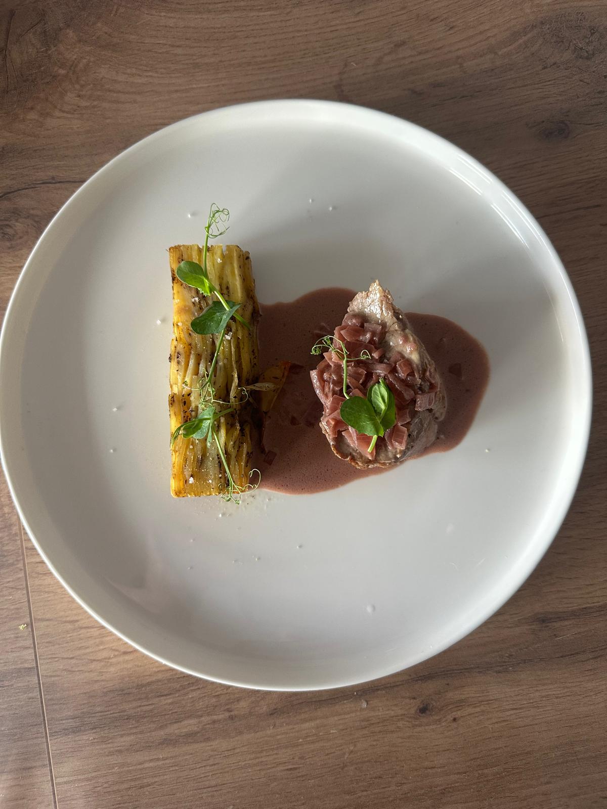 Plat gourmet avec viande sauce rouge et légumes grillés sur assiette blanche